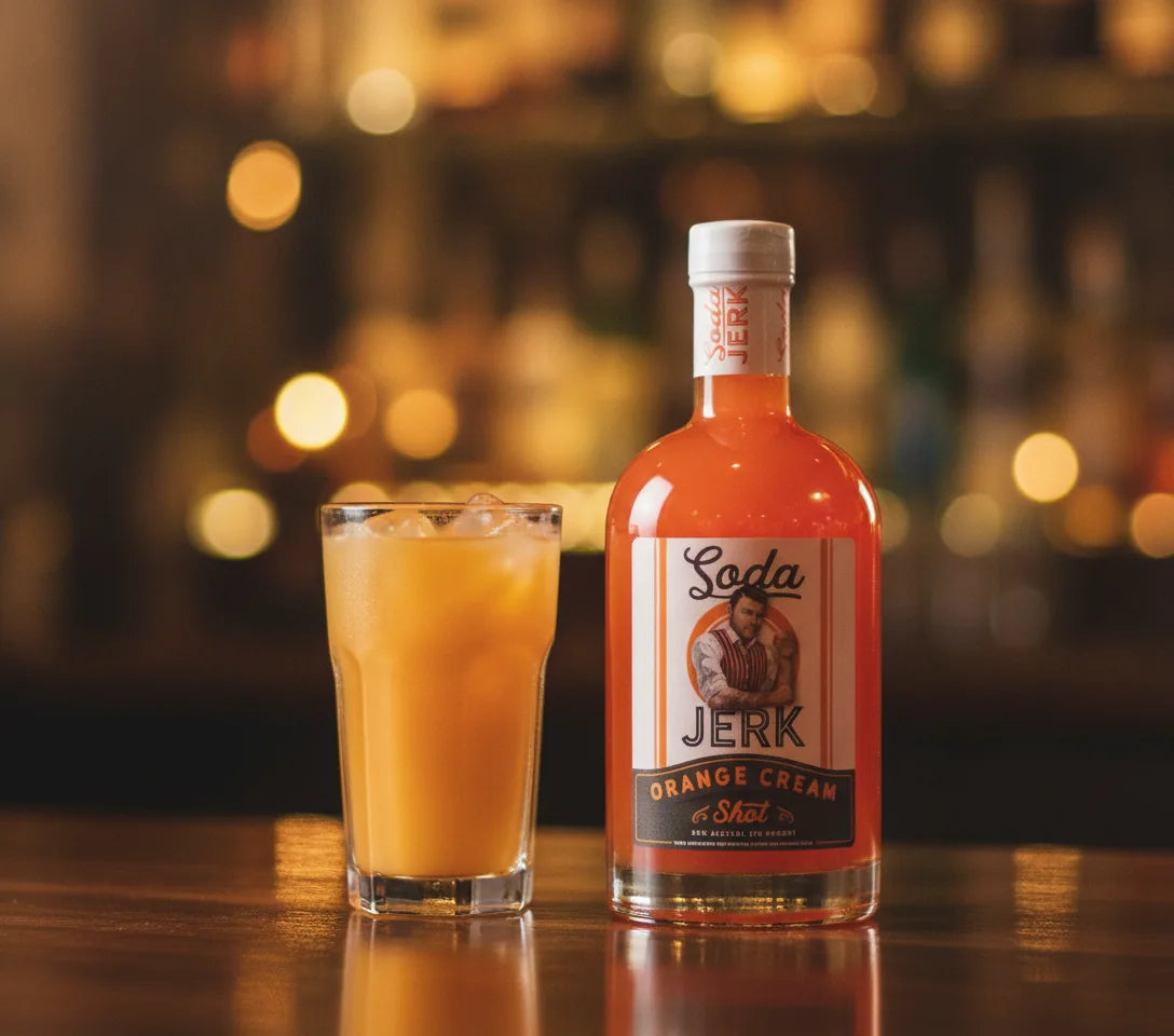 Skrewd'Driver creamsicle screwdriver cocktail with orange juice beside a Soda Jerk Orange Cream Shot bottle cocktail with Soda Jerk bottle